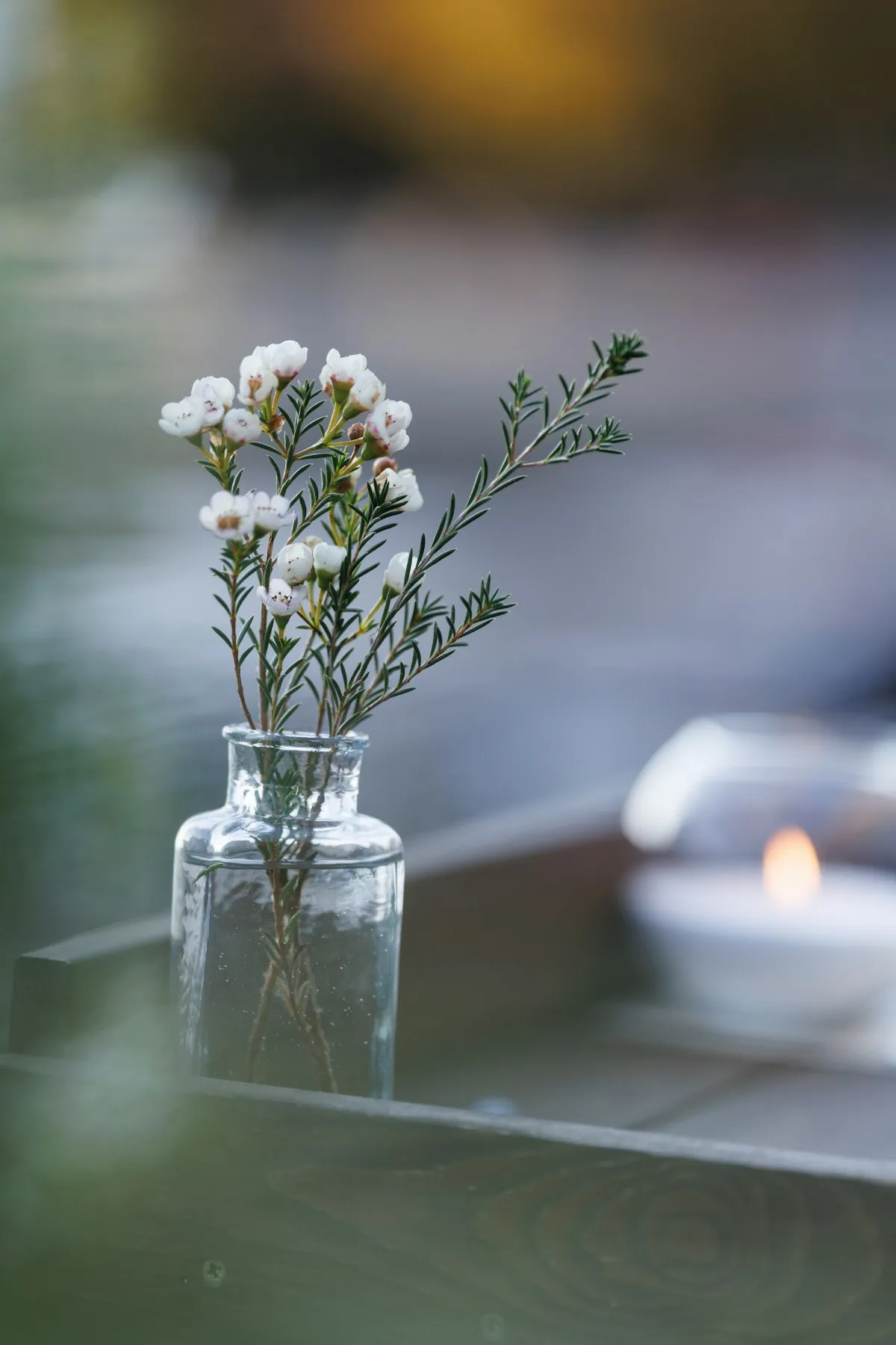Small mouth-blown glass vessel beside a lit candle