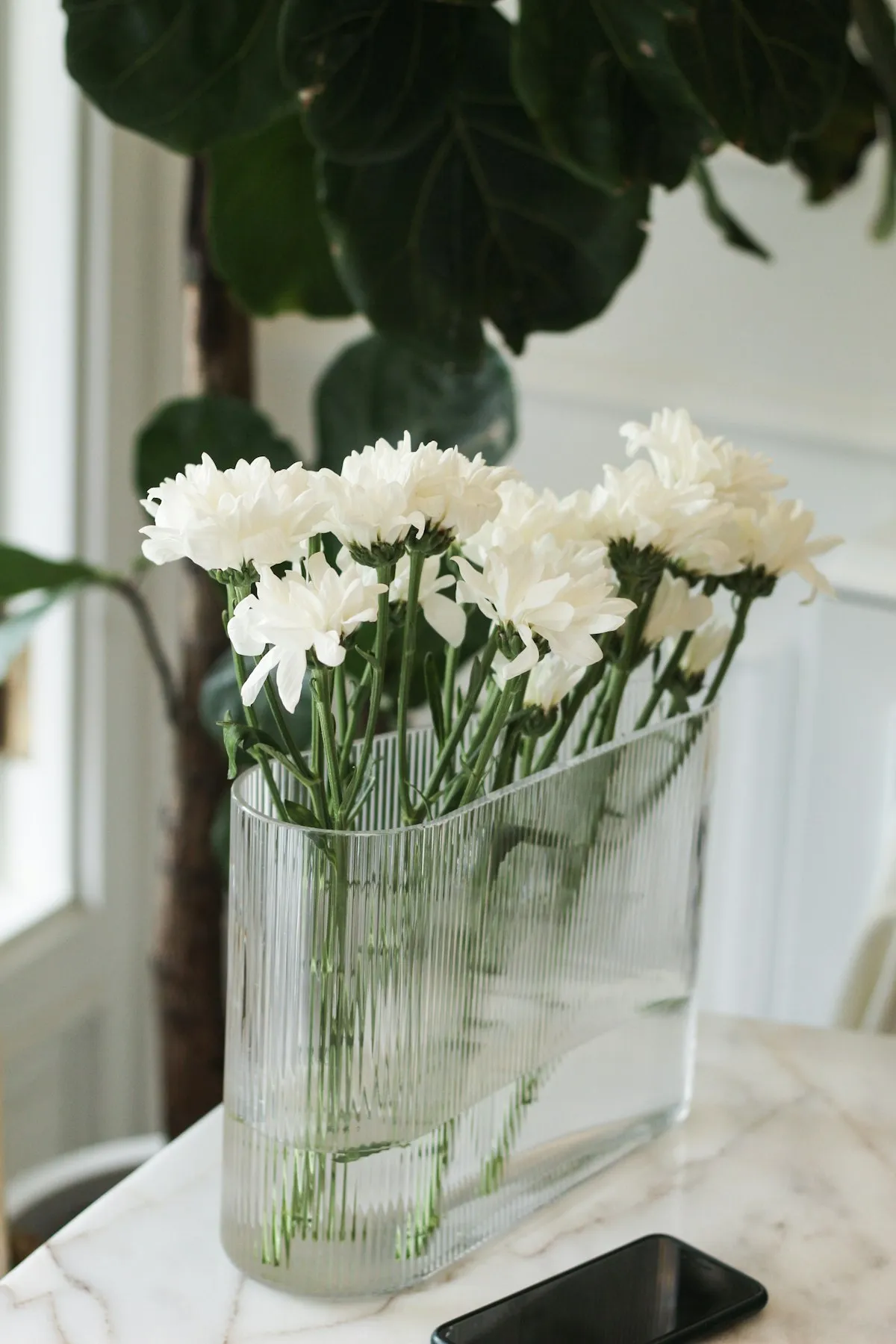 Round clear glass vase with white flowers on a table