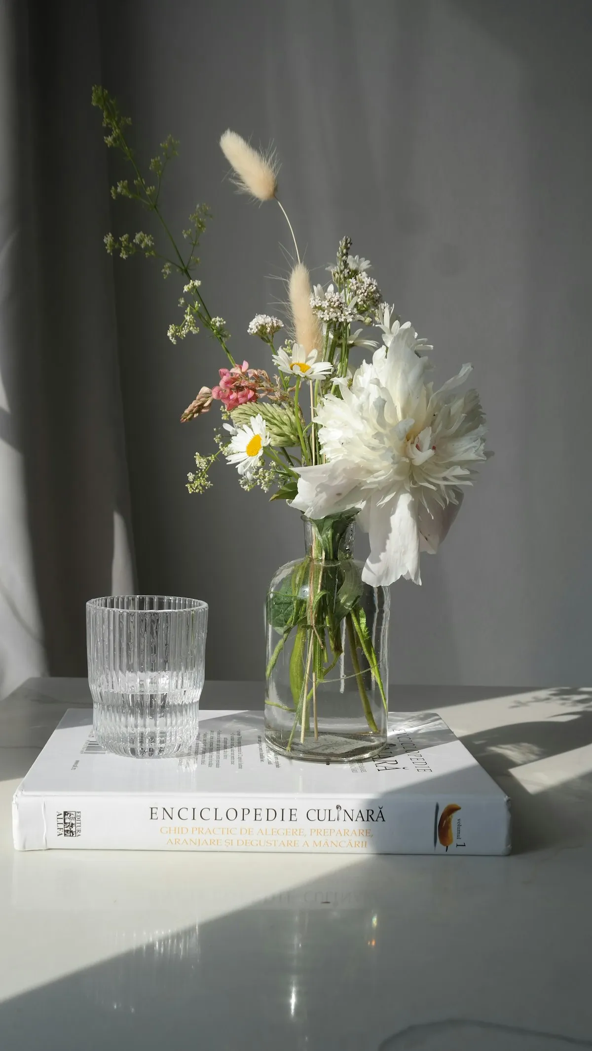 Clear mouth-blown glass vase holding white blossom